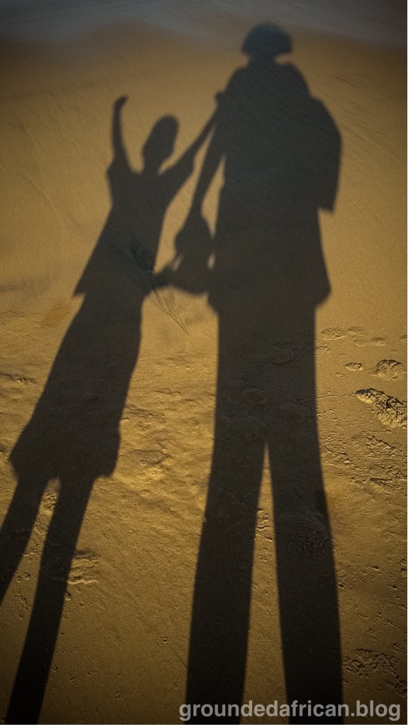 mother and son in shadow on the sand