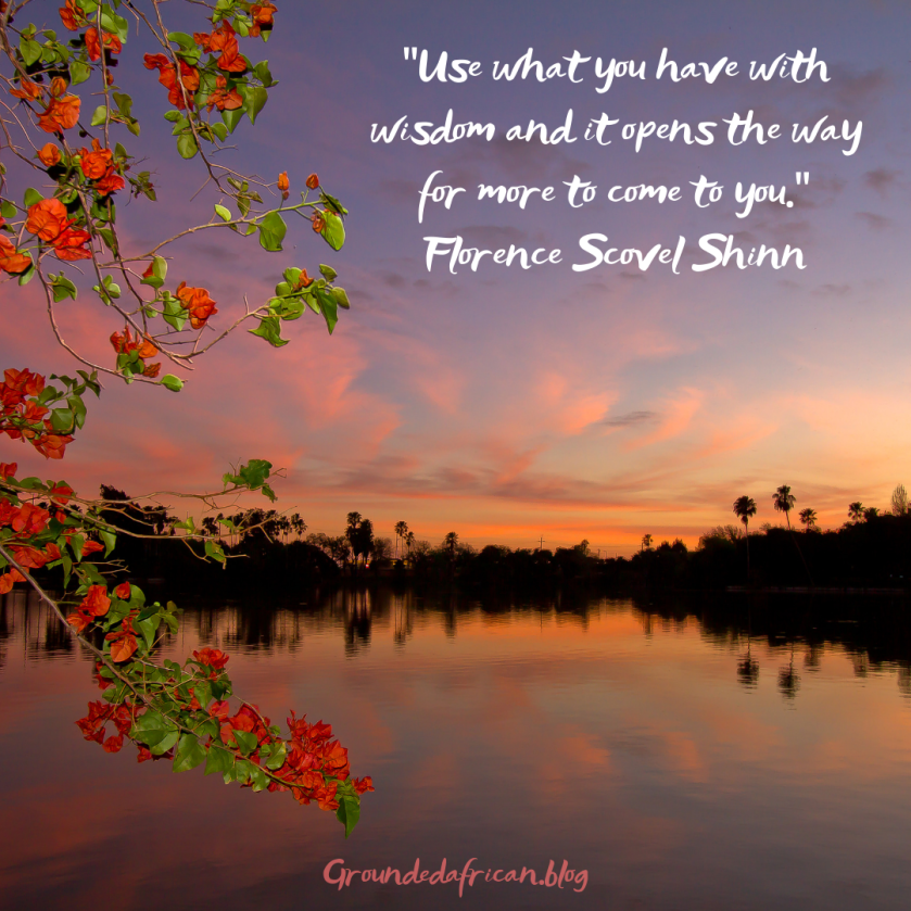 Sunrise over a lake with orange flower in foreground. Quote by Florence Scovel Shinn 