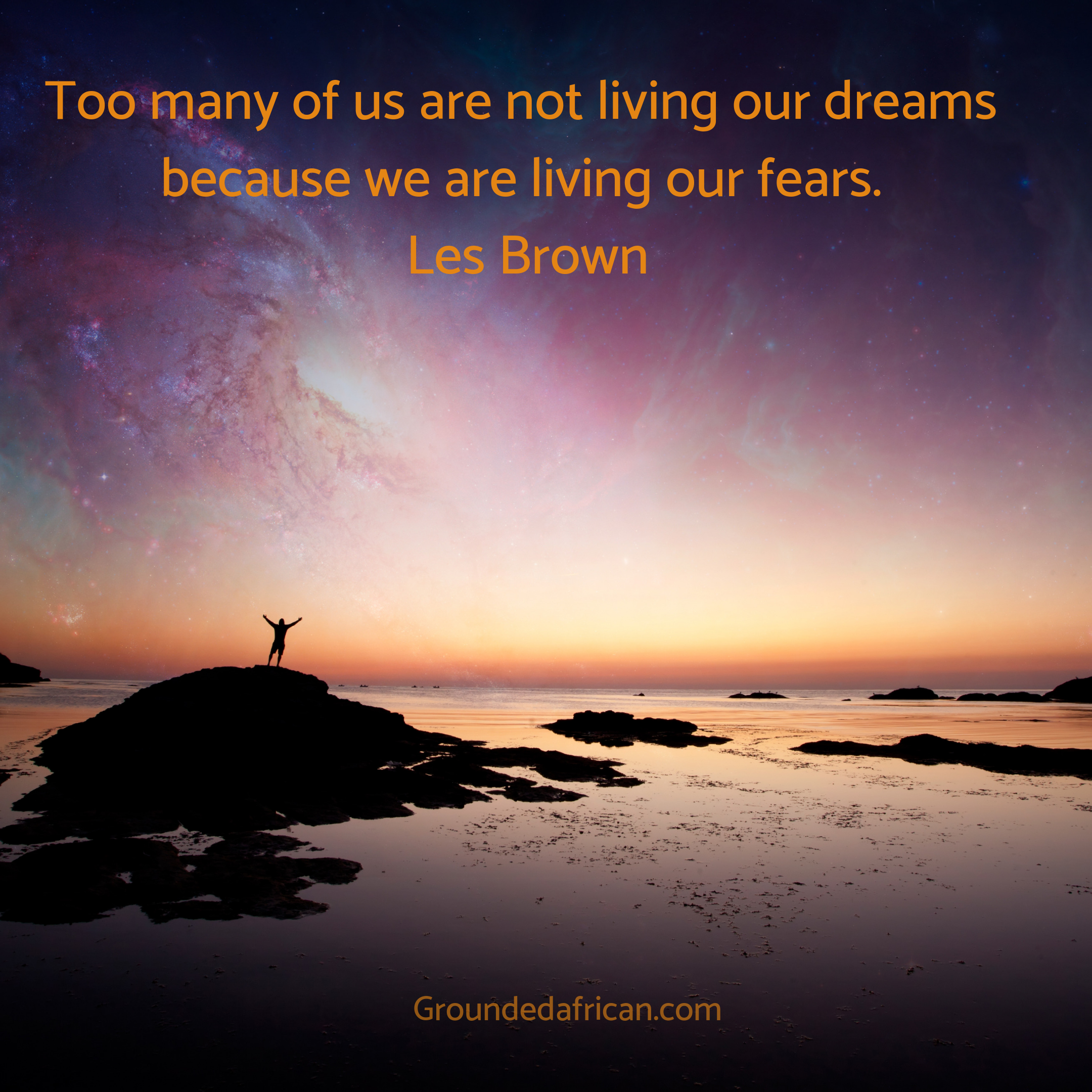 Man on rock with hands raised to the vast sky at sunset