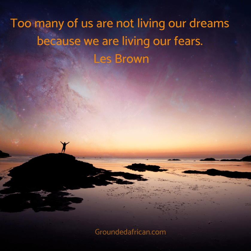 Man on rock with hands raised to the vast sky at sunset 