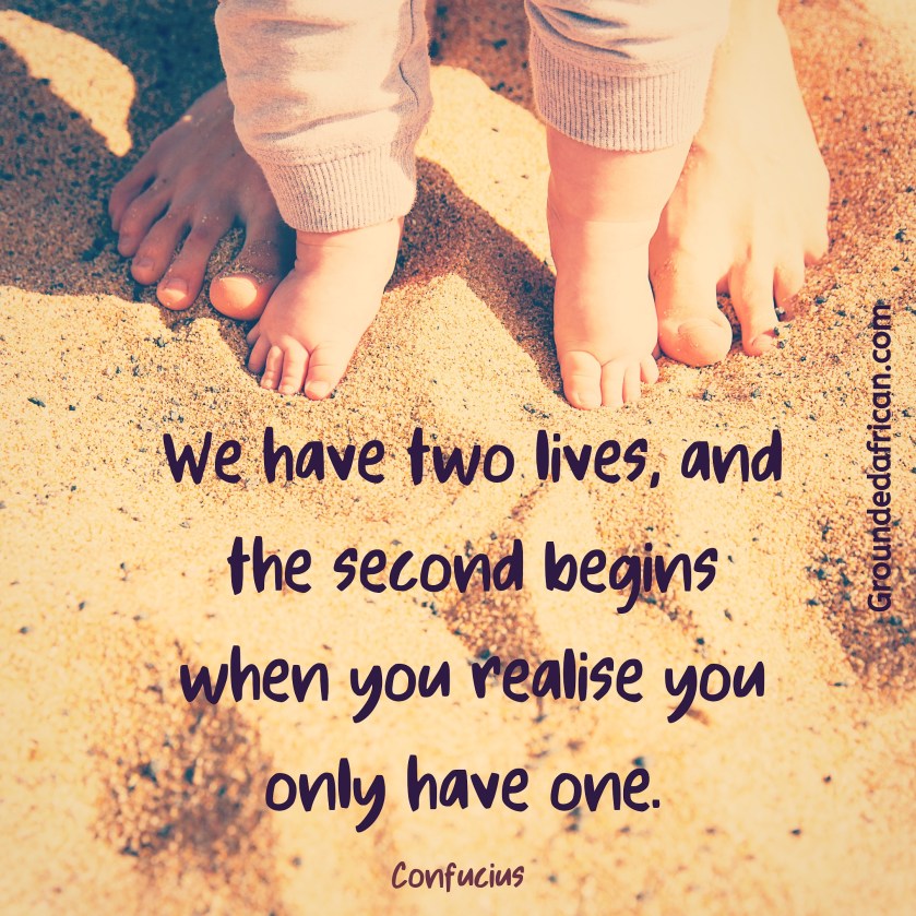 Baby feet inside parent’s feet on beach sand. Quote by Confucius 